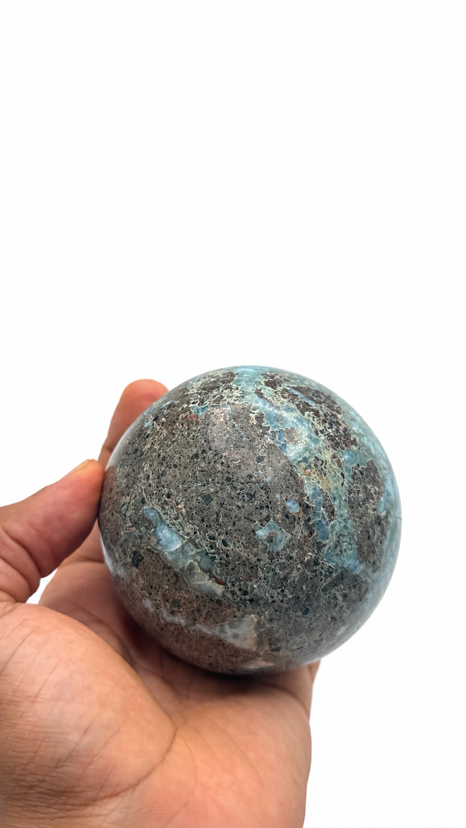 A hand holding a polished round larimar stone sphere 