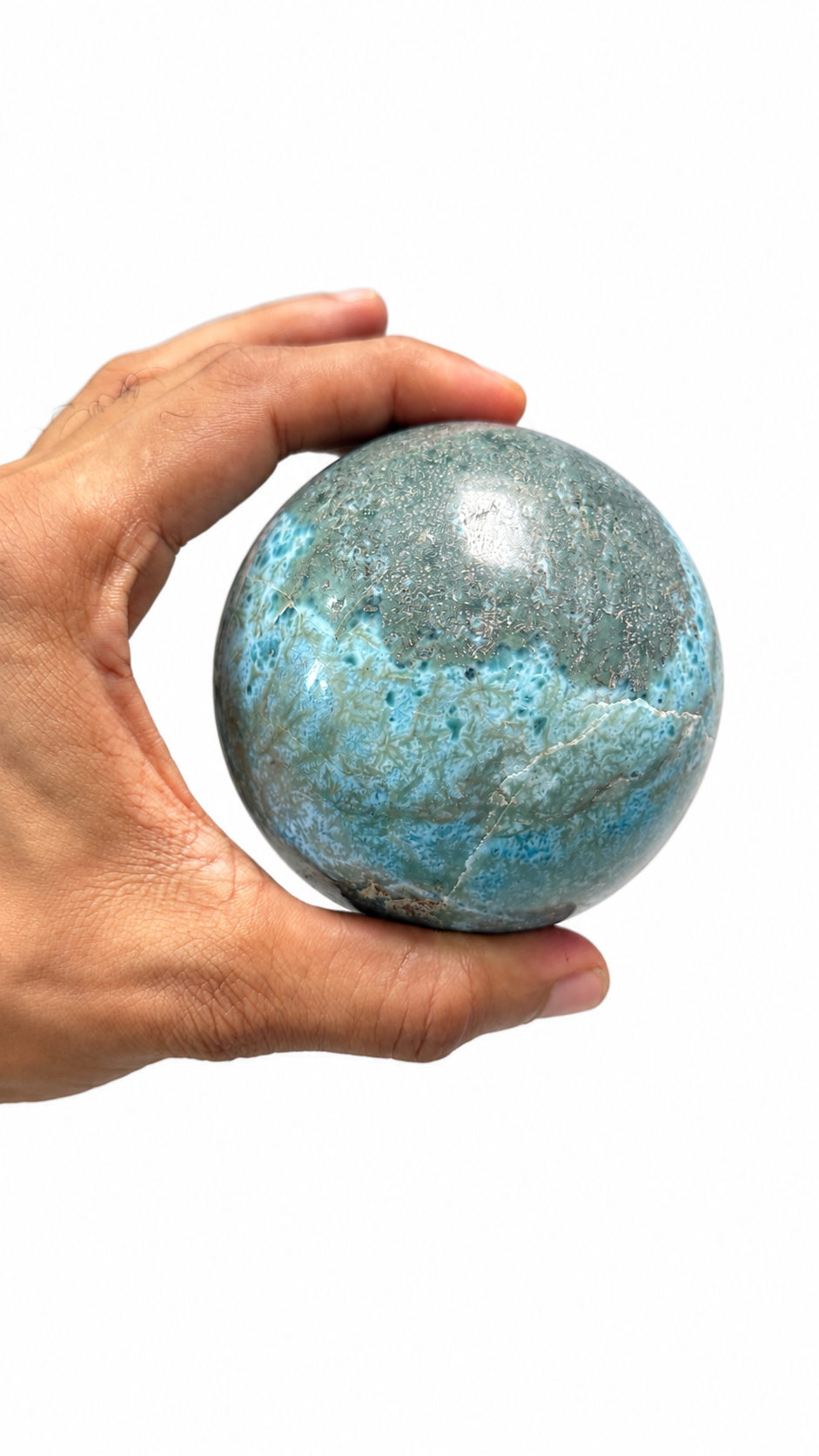 A hand holding a polished larimar sphere 