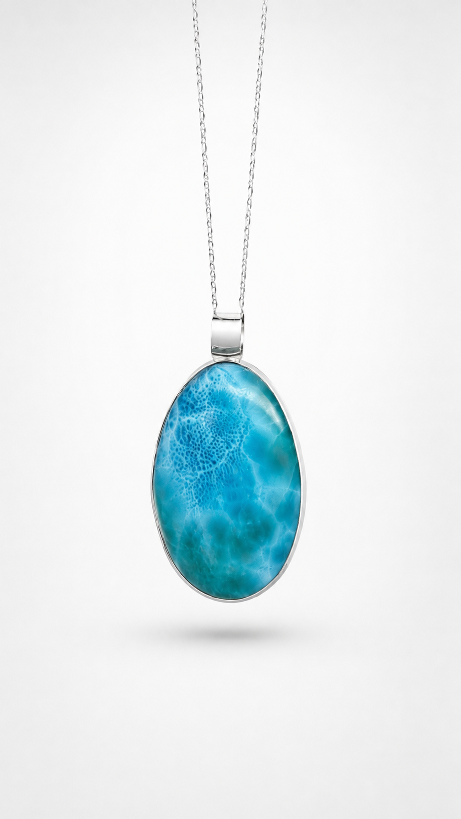 An oval pendant necklace featuring a vibrant blue and turquoise marbled pattern, set in a silver-toned bezel on a delicate silver chain, presented against a clean white background.