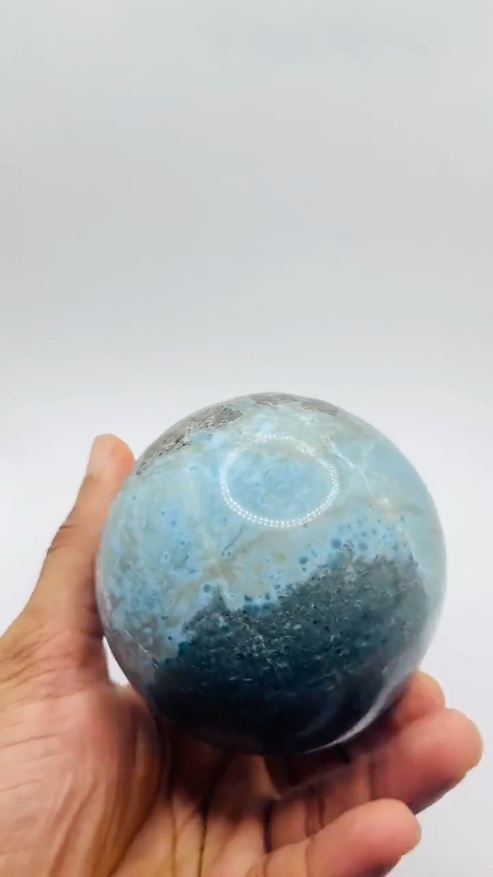 a hand showing a larimar sphere