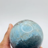 a hand showing a larimar sphere